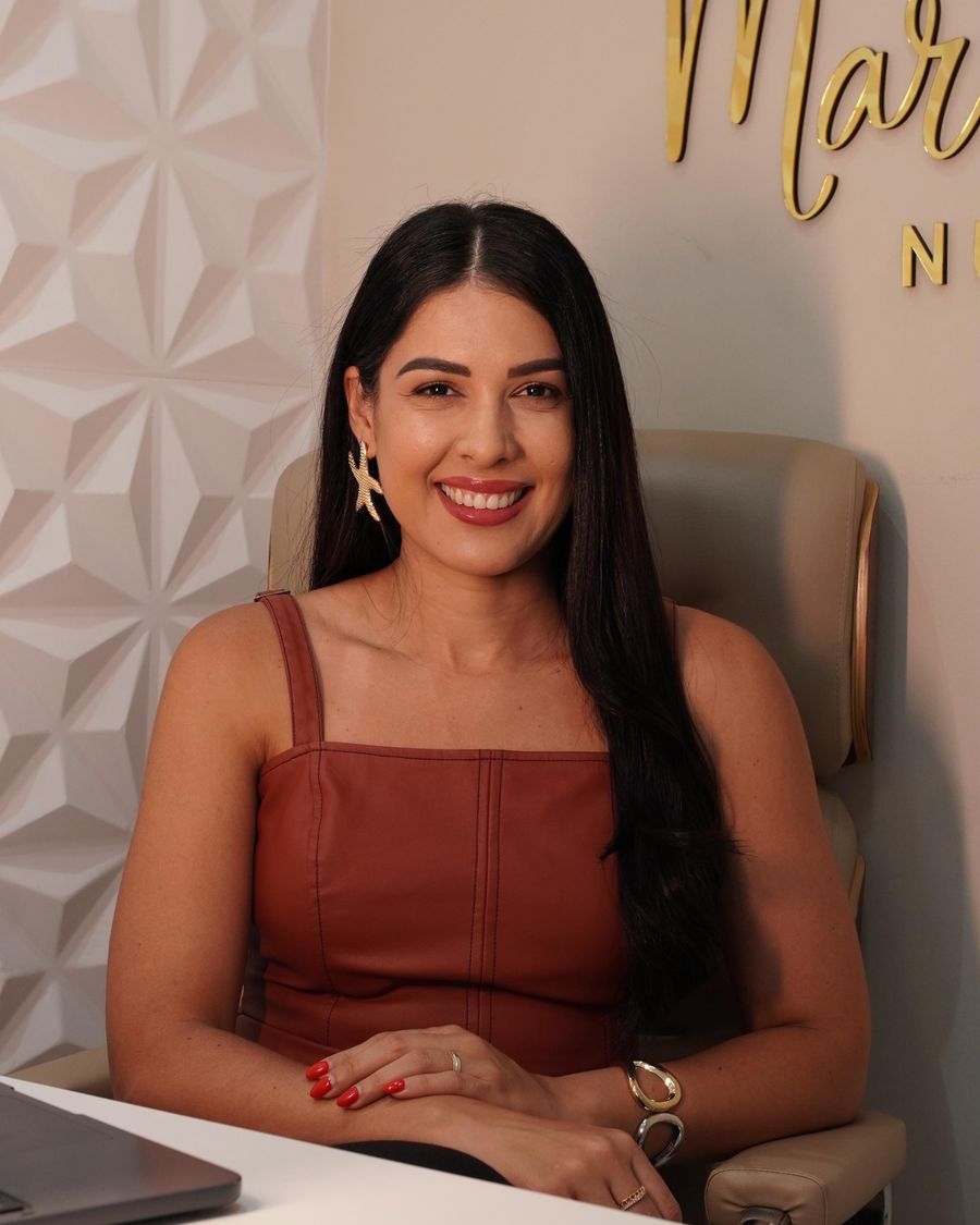 Nutricionista Marianne Soares Machado sorrindo e olhando para a câmera, sentada em seu consultório em Feira de Santana